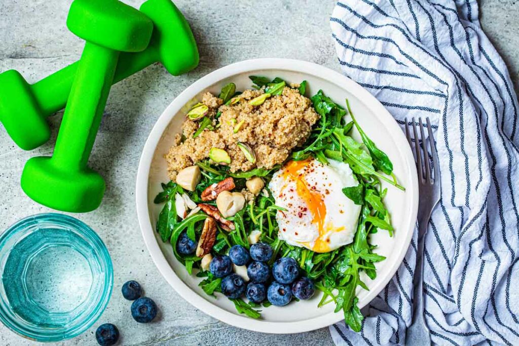 plate-of-healthy-food-next-to-green-dumbbells-and-water