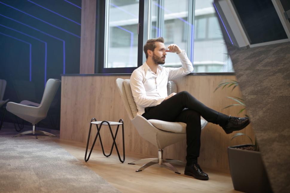 young-adult-man-sitting-on-office-chair-thinking-and-considering